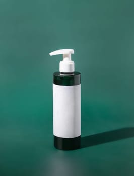 One pump refillable Plastic bottle with blank label on green close up. Packaging Mockup. Skincare beauty product, facial cleaner or lotion. Natural homemade cosmetics..