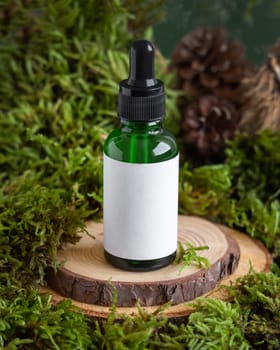 Green glass dropper bottle with blank label on wooden piece between green moss, close up, mockup. Skincare beauty product package. Natural Organic Cosmetic concept