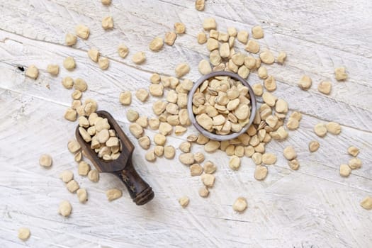 Bowl of raw dry Grass pea on wood top view. Healthy, protein source for vegan and vegetarian diet. Traditional Italian apulian cuisine ingredient. Legumes known as Cicerchia, Vetch, Blue Sweet Pea
