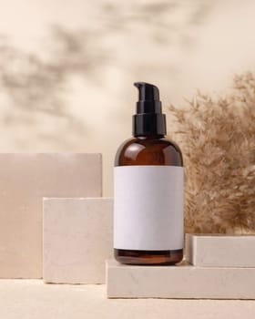 Brown one pump bottle with blank label on stones near pampas grass on light beige close up, packaging mockup. Skincare beauty product, lotion or cleanser. Natural eco friendly cosmetics