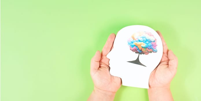 Holding a head with a colorful tree in the hands, symbol for creativity, connection to nature and positive emotion, living in a dream world