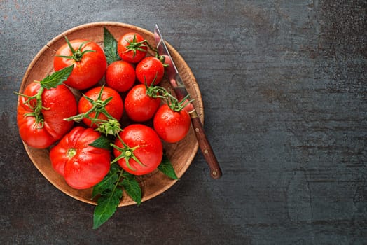 Fresh tomatoes in a plate on a dark background. Harvesting tomatoes. Top view