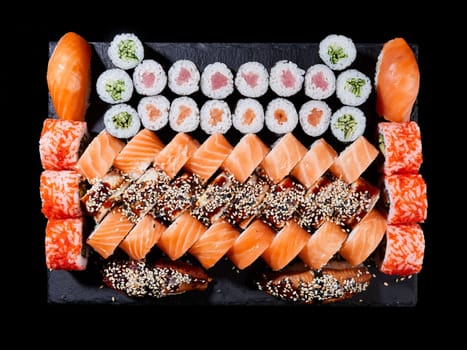 Japanese sushi food. Maki ands rolls with tuna, salmon, shrimp, crab and avocado are served on stone slate. Top view of assorted sushi. Rainbow sushi set, uramaki, hosomaki and nigiri.