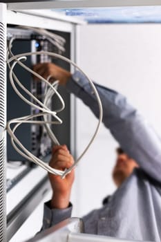 Unrecognizable man installs and connects the Internet cable to the fuse box. Bottom view close up of white twisted wires in hands of man laying wiring for Wi-Fi router. Selective focus.