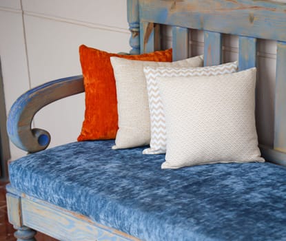 Four colored cushions stand on a wooden bench.