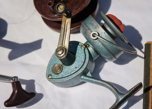 An old fishing reel without a fishing rod on a table.