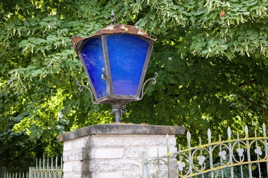A lantern with blue discson a gatepost.