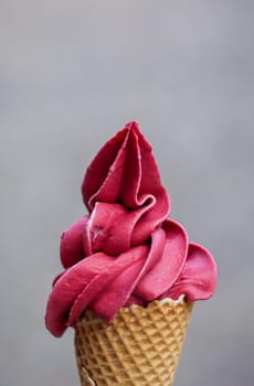 A waffle ice cream cone filled with a delicious freshly made raspberry soft serve ice cream.