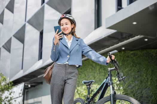 Happy lifestyle business female commuting outside in morning, Asian smiling young woman use smart mobile phone talk with business during go to office work at city street with bicycle, Eco friendly