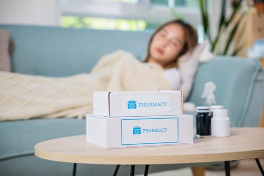 Asian beautiful female use pharmacy first aid kit box delivery service from hospital, Young woman tired sick she sleep and resting on sofa after take medicines pills in living room at home, healthcare
