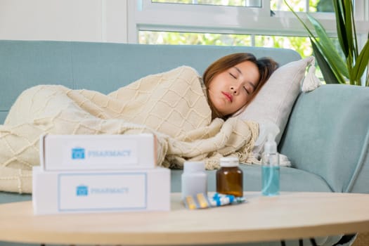 Asian young woman tired sick she sleep and resting on sofa after take medicines pills in living room at home, beautiful female use pharmacy first aid kit box delivery service from hospital, healthcare