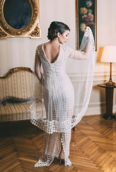 Beautiful bride posing in designer wedding dress in classical luxury interior.