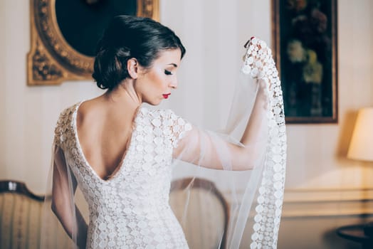 Beautiful bride posing  in designer wedding dress in classical luxury interior.