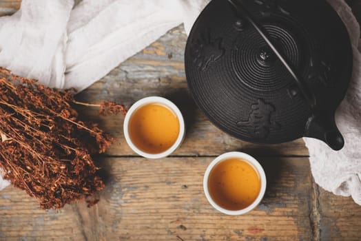 Traditional japanese herbal tea recipe prepared in cast iron teapot with organic dry herbs. Top view of asian traditional hot beverage on wooden table.