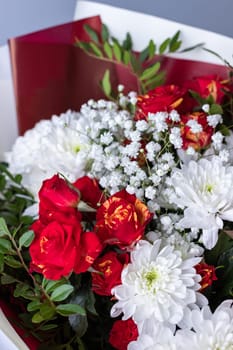 Close up bouquet of pink roses, white chrysanthemums, gypsophila and sprigs of greenery. Concept of giving flowers and compliments. Nature background. Selective focus.