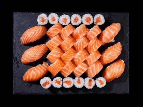 Top view sushi rolls philadelphia, sashimi and maki on a black slate plate. Large sushi roll set with salmon on a black slate plate.