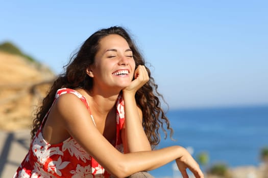 Happy woman in red dress laughing on the beach