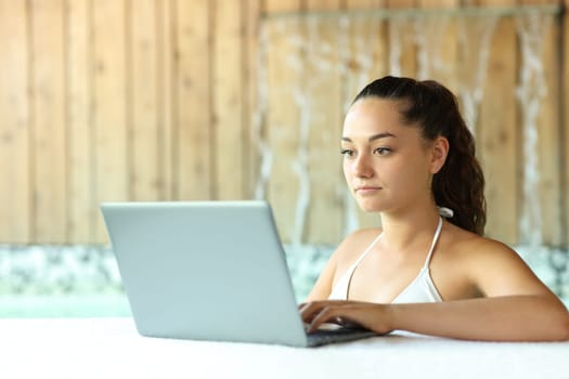 Woman unable to relax using laptop in a spa
