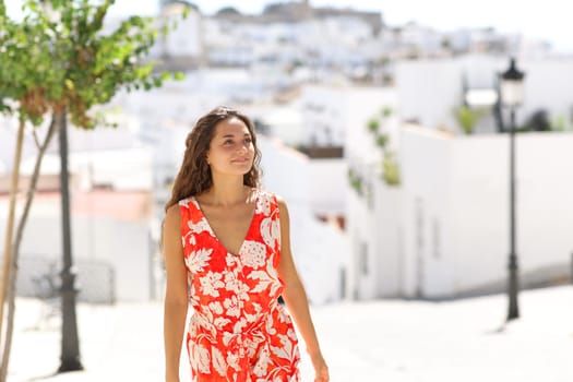 Happy woman in red walking in a white town street on summer vacation