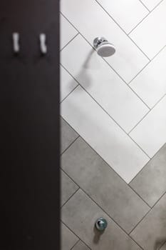 Shower equipment. Stylish minimalist shower head built into wall in modern bathroom. Shower funnel on the wall with white and gray tiles. Sale of plumbing concept.