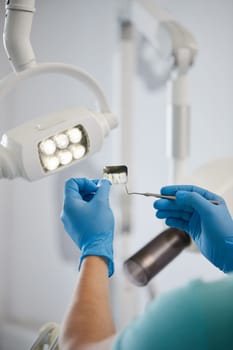 Expertise of dental radiogram. Close up x-ray of several teeth in hands of dentist who will conduct diagnosis. Hands of male dentist in gloves holding picture of patient's teeth.