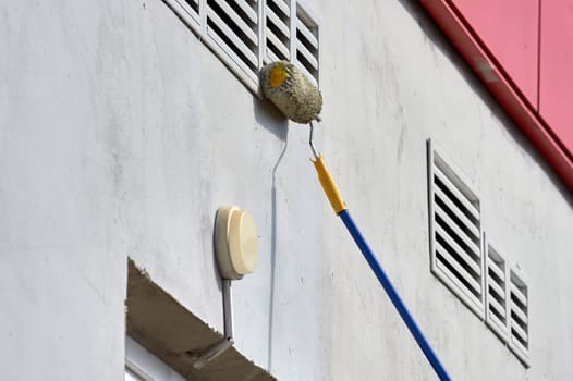 painting the street wall with a roller with gray paint. High quality photo