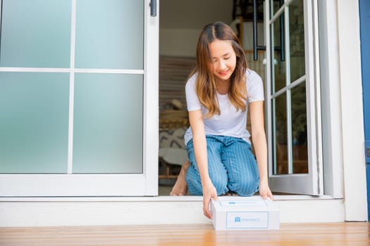 Close up hands of sick Asian woman sitting at door to receive medication first aid pharmacy box from hospital delivery service at floor home, merchandise medicine online business, healthcare concept