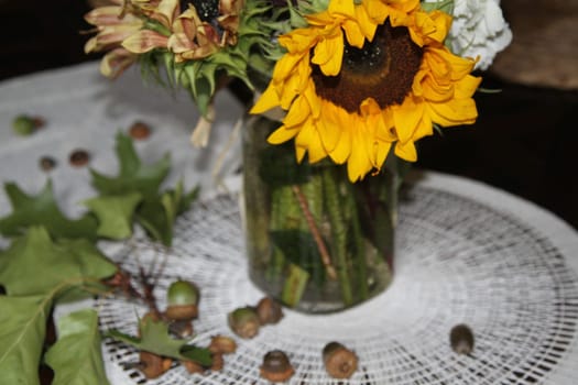 Mason jar with sunflowers and wildflowers bouquet, oak leaves and acorns