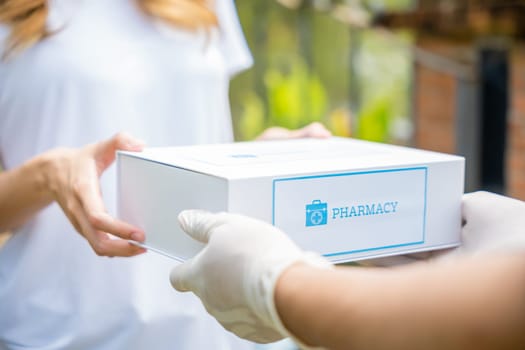 Sick Asian young woman receive medication first aid pharmacy box from hospital delivery service, delivery man give medicine drug to patient female at home, healthcare medicine online concept