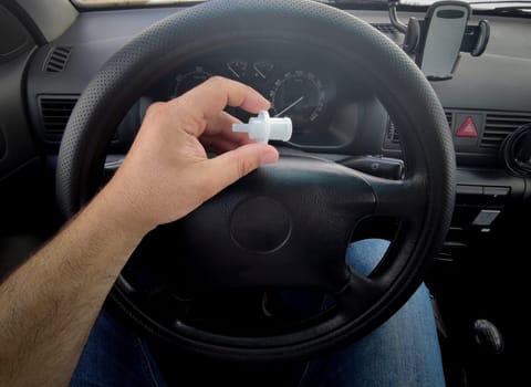 Driver holds breathalyzer mouthpiece sitting in the car. Point of view shot