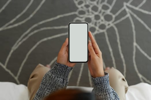 women holding phone sitting on bed in bedroom