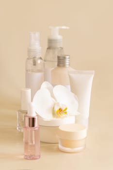 Natural cosmetic jars and skin care accesories with white orchid flower on light beige close up. Beauty products for everyday woman face care routine, Spa Treatments