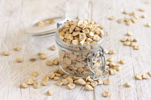 Glass jar of raw dry Grass pea on wood close up. Healthy, protein source for vegan and vegetarian diet. Traditional Italian apulian cuisine ingredient. Legumes known as Cicerchia, Vetch, Blue Sweet Pea