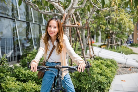 Happy Asian beautiful young woman riding bicycle on street outdoor near building city, Portrait of smiling female lifestyle using bike in summer travel means of transportation, ECO friendly