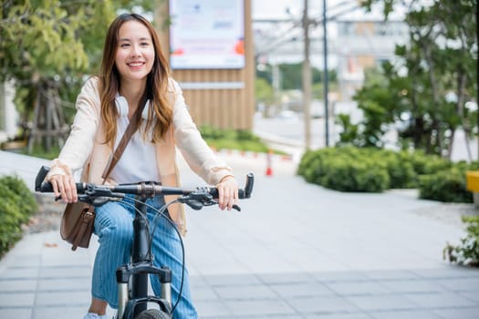 Happy Asian young woman riding bicycle on street outdoor near building city, Portrait of smiling female lifestyle use mountain bike in summer travel means of transportation, ECO friendly, Urban biking