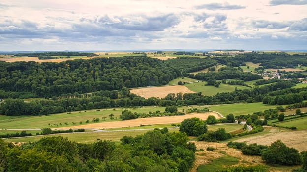 Cornfields on which bales of straw remain after harvest. Wheat was harvested. Food and fodder for livestock. Landscape shot of fields and meadows with trees and path.