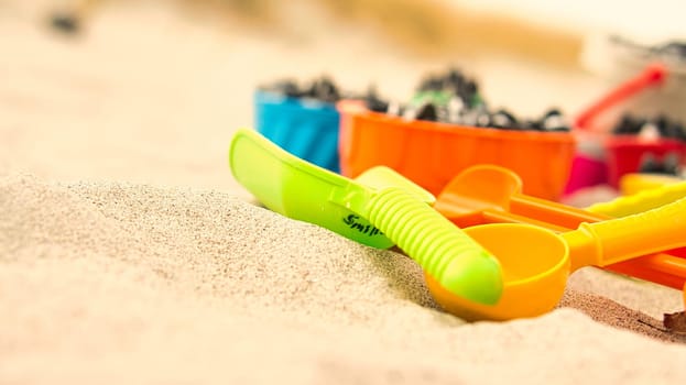 colorful toys on the beach for children to dig. Sand is used to build castles and shapes. Beach vacation with the family and fun for the little kids.