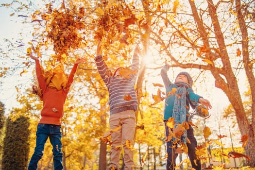 Children playing together in colourful natural park in autumnal day. Concept of friendship and family weekend.