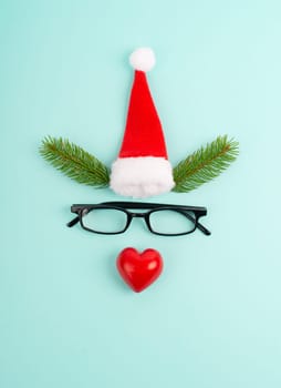 Face of a reindeer with a red heart nose, fir antlers, a santa claus hat and eyeglasses, merry christmas greeting card