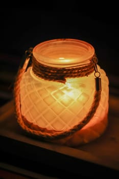 A glass with a lit tea light as table lighting in the evening.
