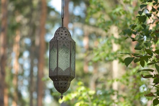Hanging lamp on a track in front of a forest of metal and glass. Oriental processing. Object photo
