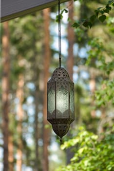 Hanging lamp on a track in front of a forest of metal and glass. Illuminated. Oriental processing. Object photo