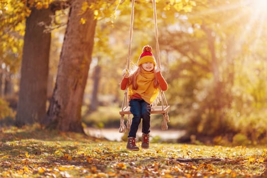 Cute girl swinging on the swing n the sunny park. Concept of the healthy lifestyle.