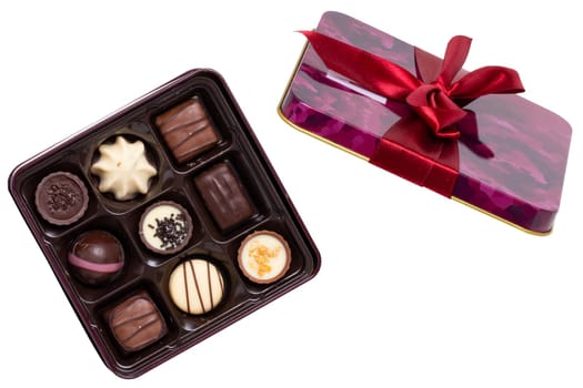 Closeup of box of fine chocolate candies in a beautiful plastic box isolated on a white background. Surprise gift for Valentine's Day or other festive occasions. Macro.