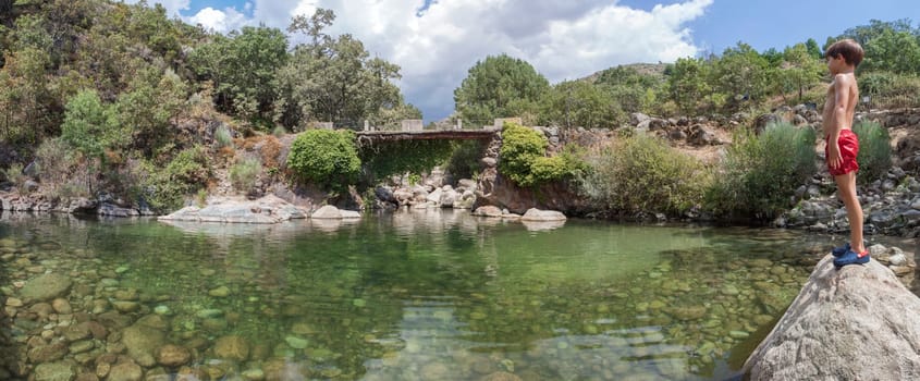 Child boy at La Maquina Natural swimming pool. Crystal-clear waters spot in the heart of La Vera County, Caceres, Extremadura, Spain