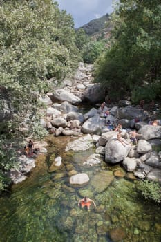 Guijo de Sta Barbara - August 25th, 2022: Visitors enjoying La Maquina Natural swimming pool, Guijo de Santa Barbara, Spain. Crystal-clear waters spot in the heart of La Vera County, Caceres, Extremadura