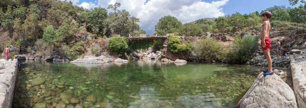 Child boy at La Maquina Natural swimming pool. Crystal-clear waters spot in the heart of La Vera County, Caceres, Extremadura, Spain
