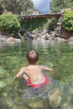 Child boy at La Maquina Natural swimming pool. Crystal-clear waters spot in the heart of La Vera County, Caceres, Extremadura, Spain