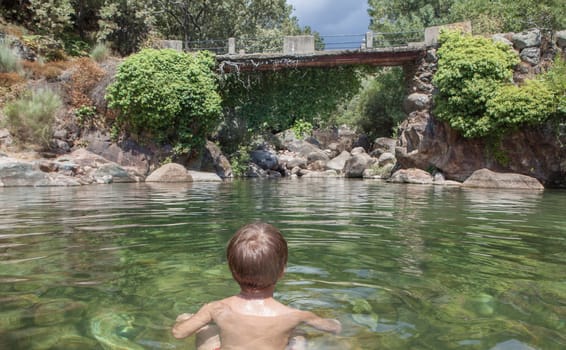 Child boy at La Maquina Natural swimming pool. Crystal-clear waters spot in the heart of La Vera County, Caceres, Extremadura, Spain