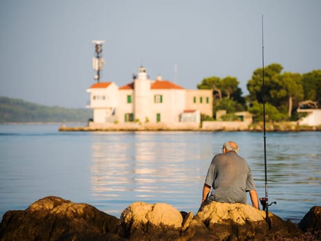 pensioner is sitting and fishing on canal of sveti ante in sibenik croatia